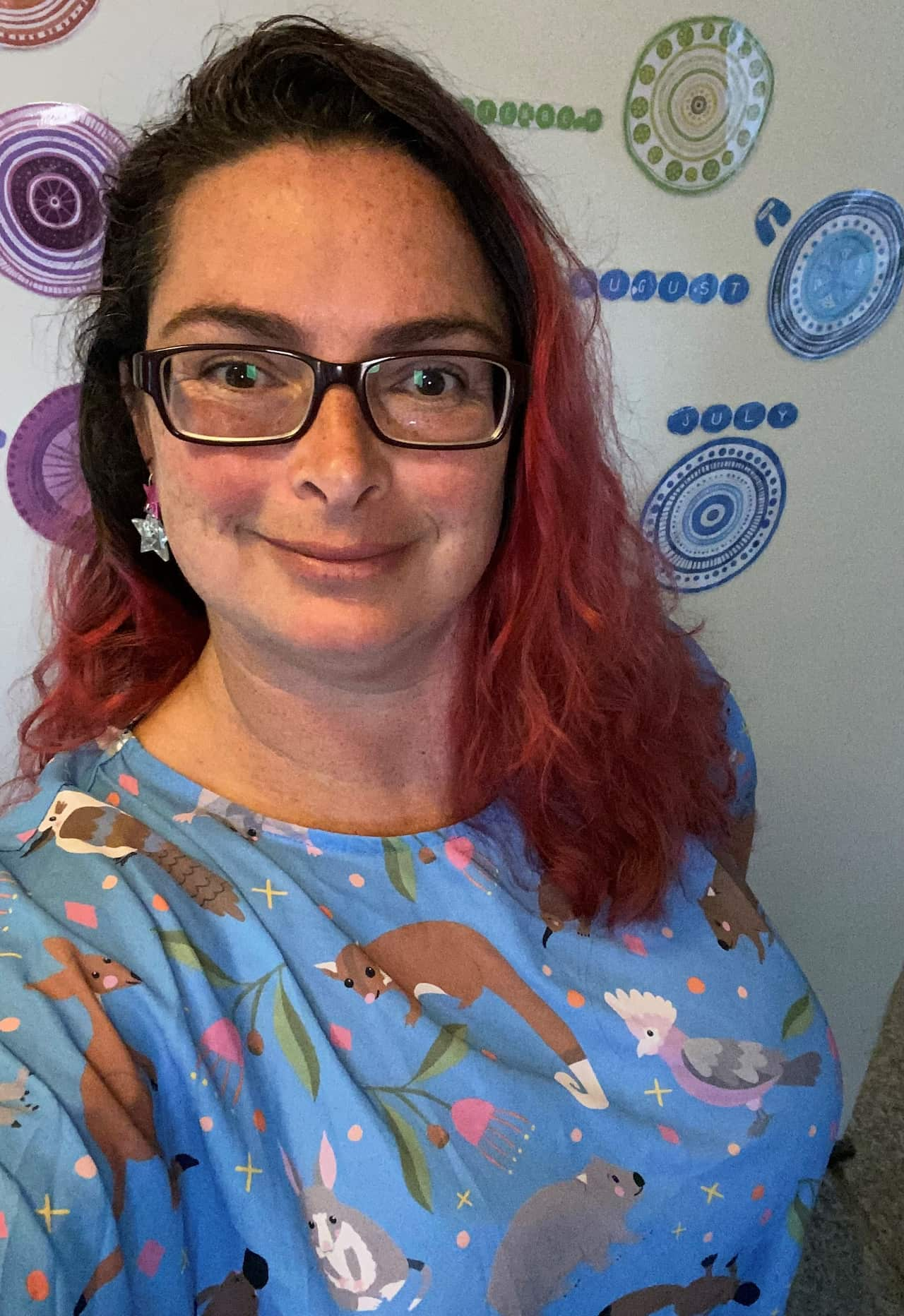 A woman wearing a bright blue dress featuring native animals on it