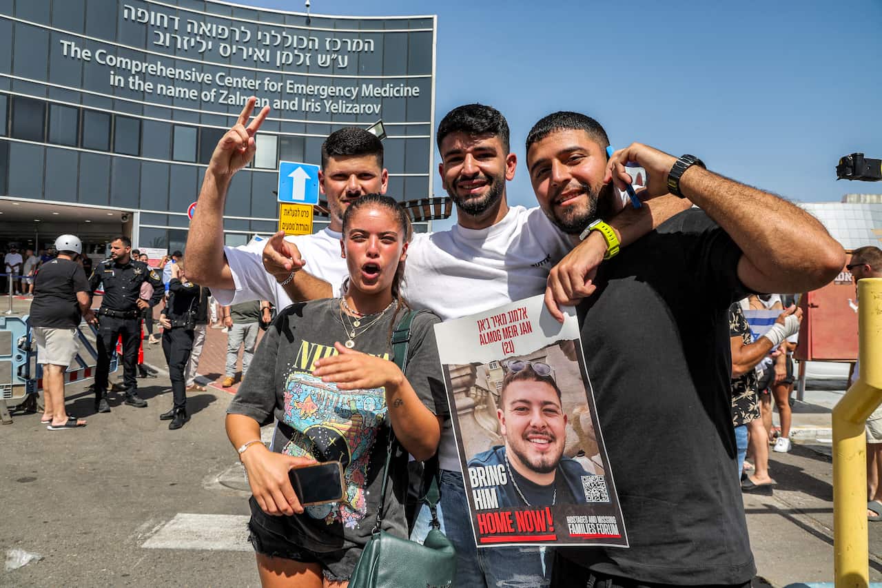 Four people hold a poster of a person and celebrate.