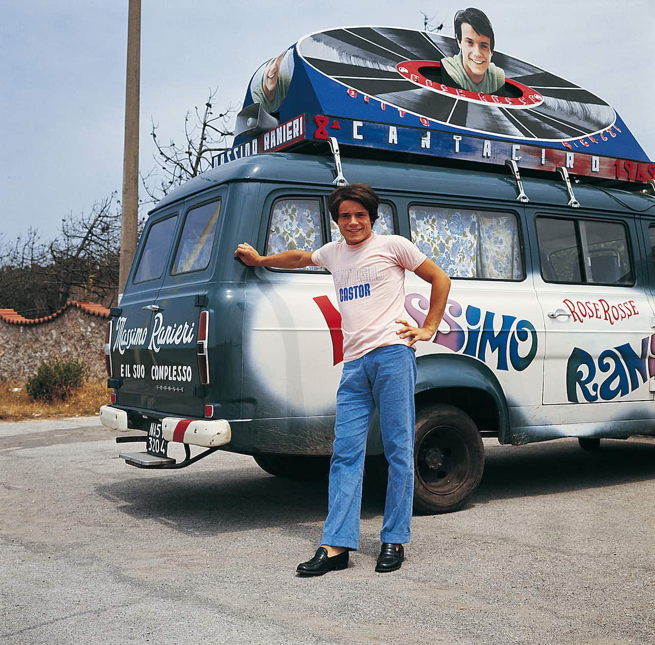 Italian singer Massimo Ranieri posing beside a van with a poster advertising his participation in the 8th Cantagiro with the song 'Rose Rosse'.