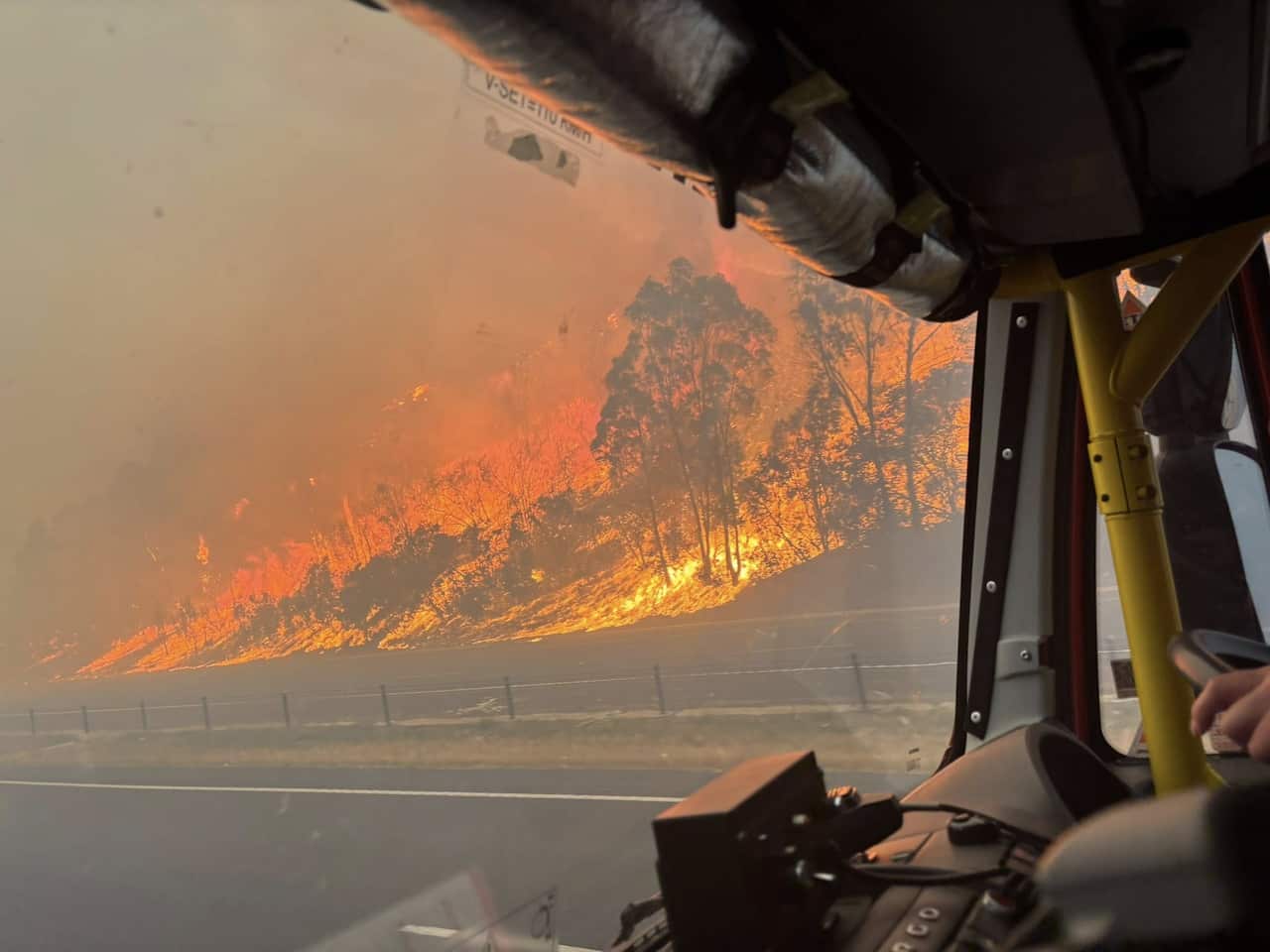 A bushfire burning on the side of a road