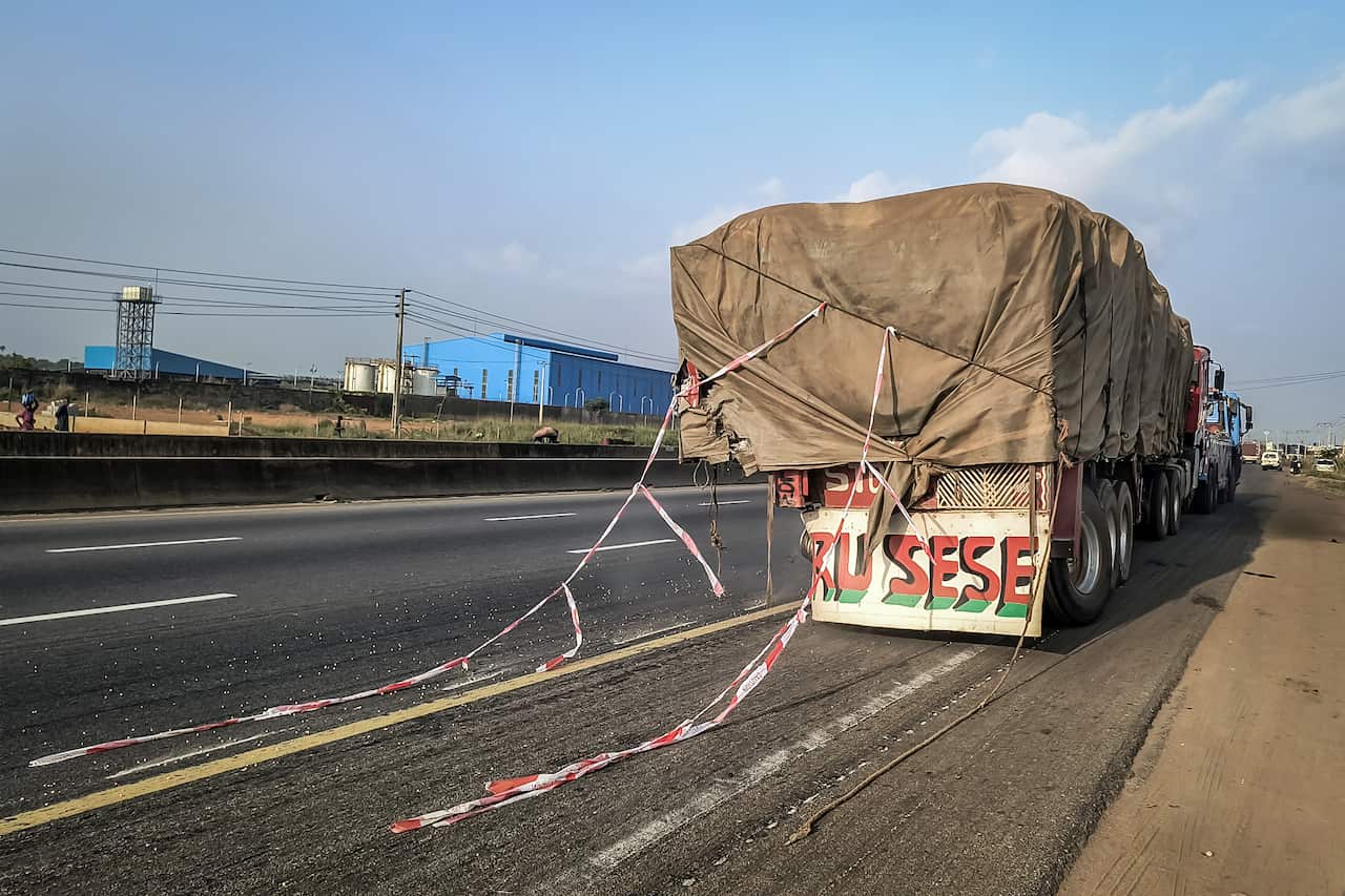 An 18-wheeler truck is on the side of a highway.