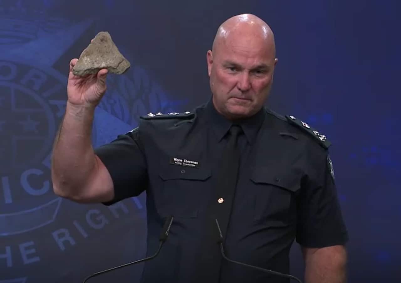 A police officer holds up a rock during a press conference.
