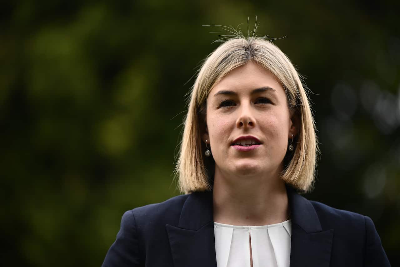 A woman with short blonde hair wearing a blue jacket and a white shirt