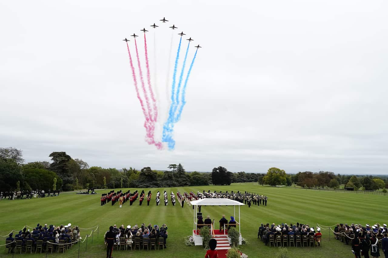 Aeroplanes fly in the sky, letting out red, white and blue smoke. 