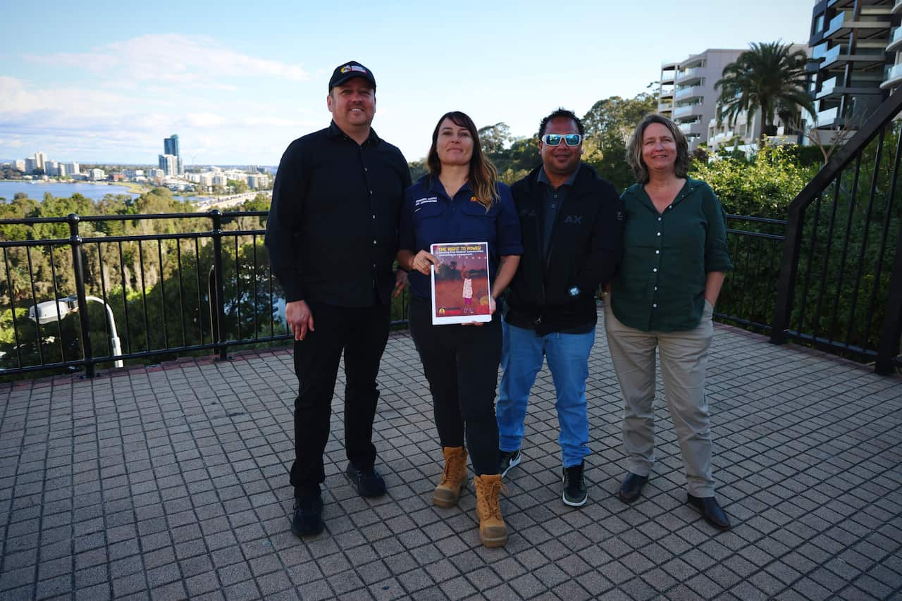 Four people holding a document, with a city skyline in the background.