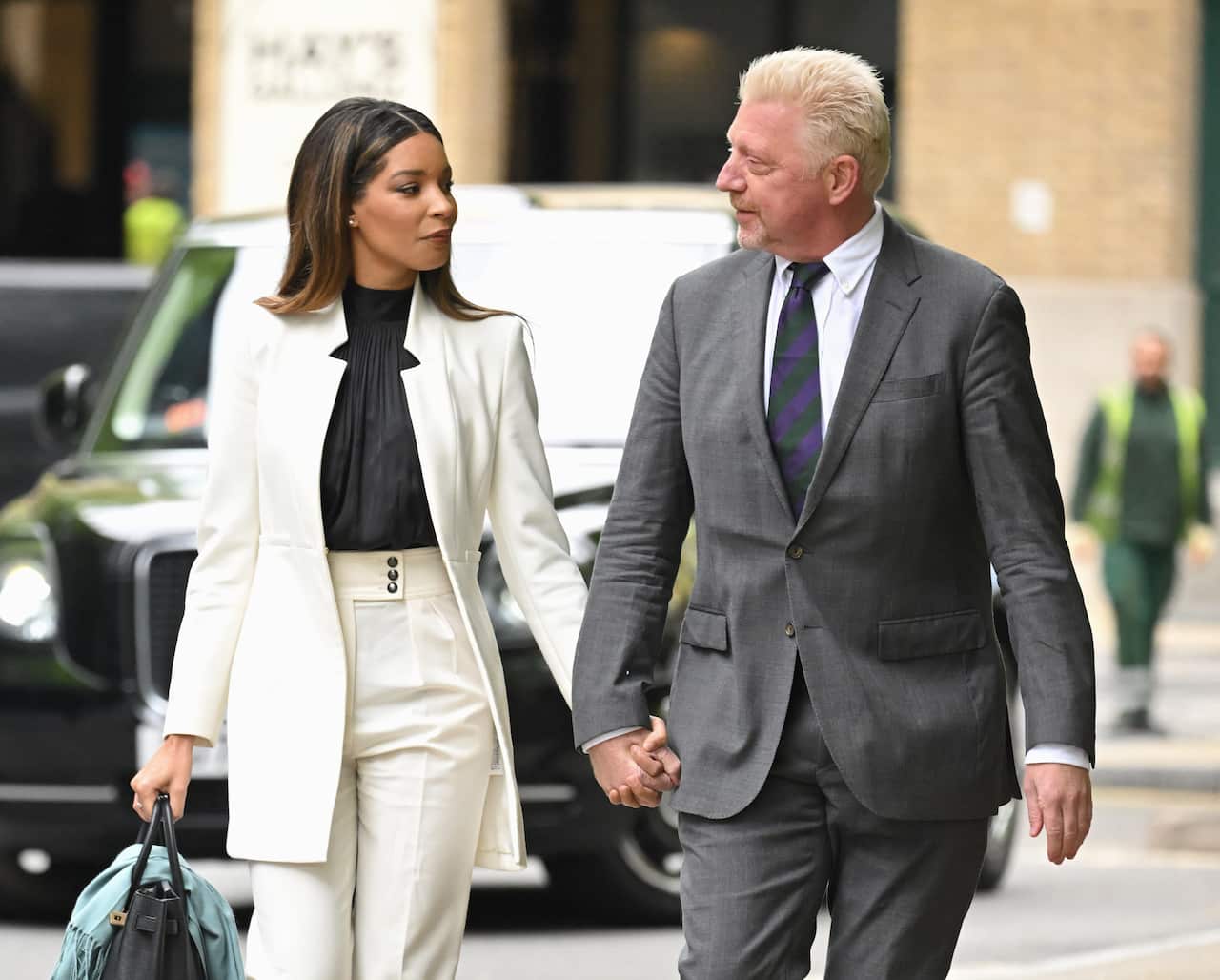 A woman and a man holding hands while walking.