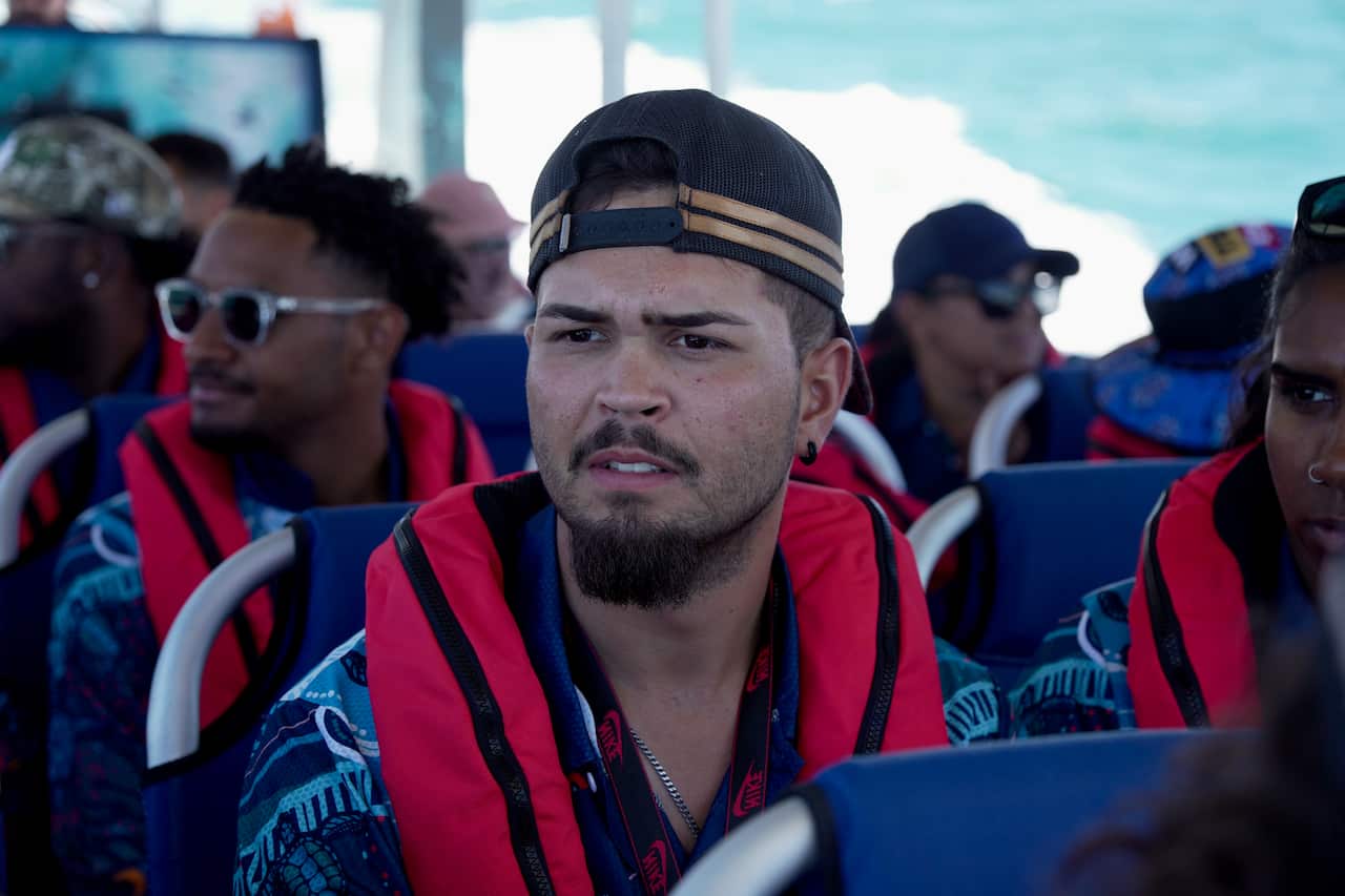 Man looking into distance wearing red life jacket on boat