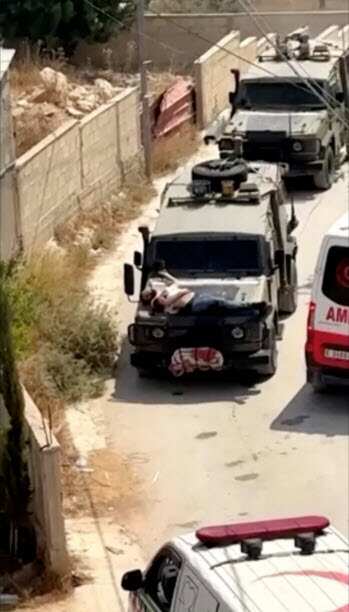 A man strapped to a military vehicle
