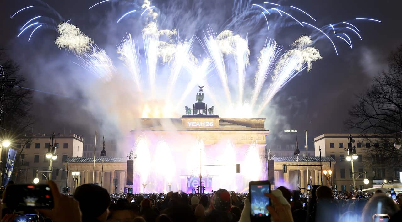 Fireworks over a grand landmark, with crowds watching on.