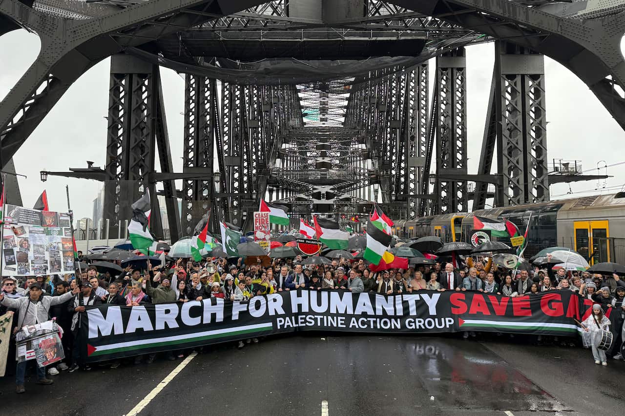 Los manifestantes se unen con un letrero en el puente del puerto de Sydney.