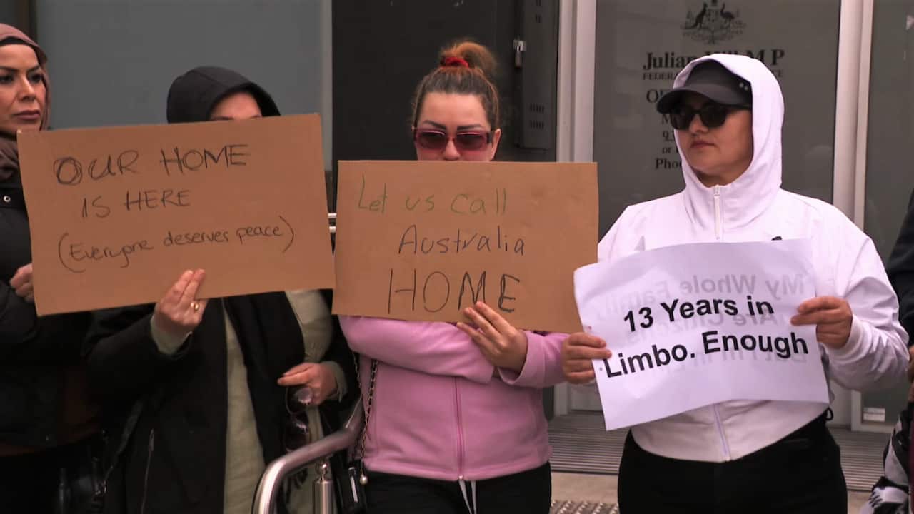 Three women holding up signs reading 'OUR HOME IS HERE (everyone deserves peace)', 'Let us call Australia HOME', and '13 years in Limbo. Enough'.