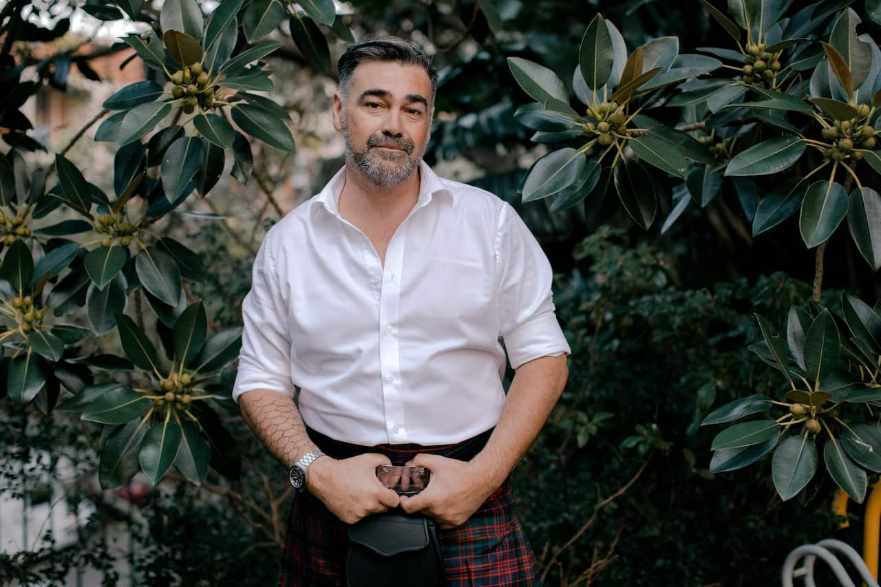 Man standing in garden wearing a kilt. 