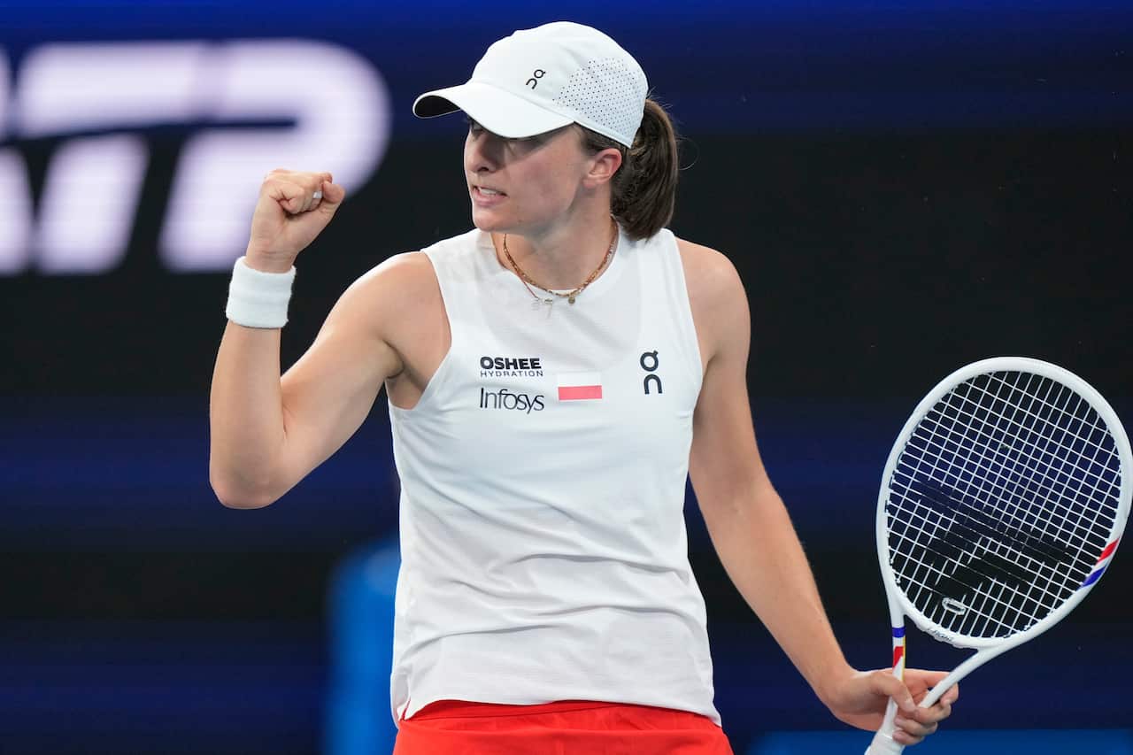 Una mujer sostiene una raqueta de tenis y levanta el puño en el aire.