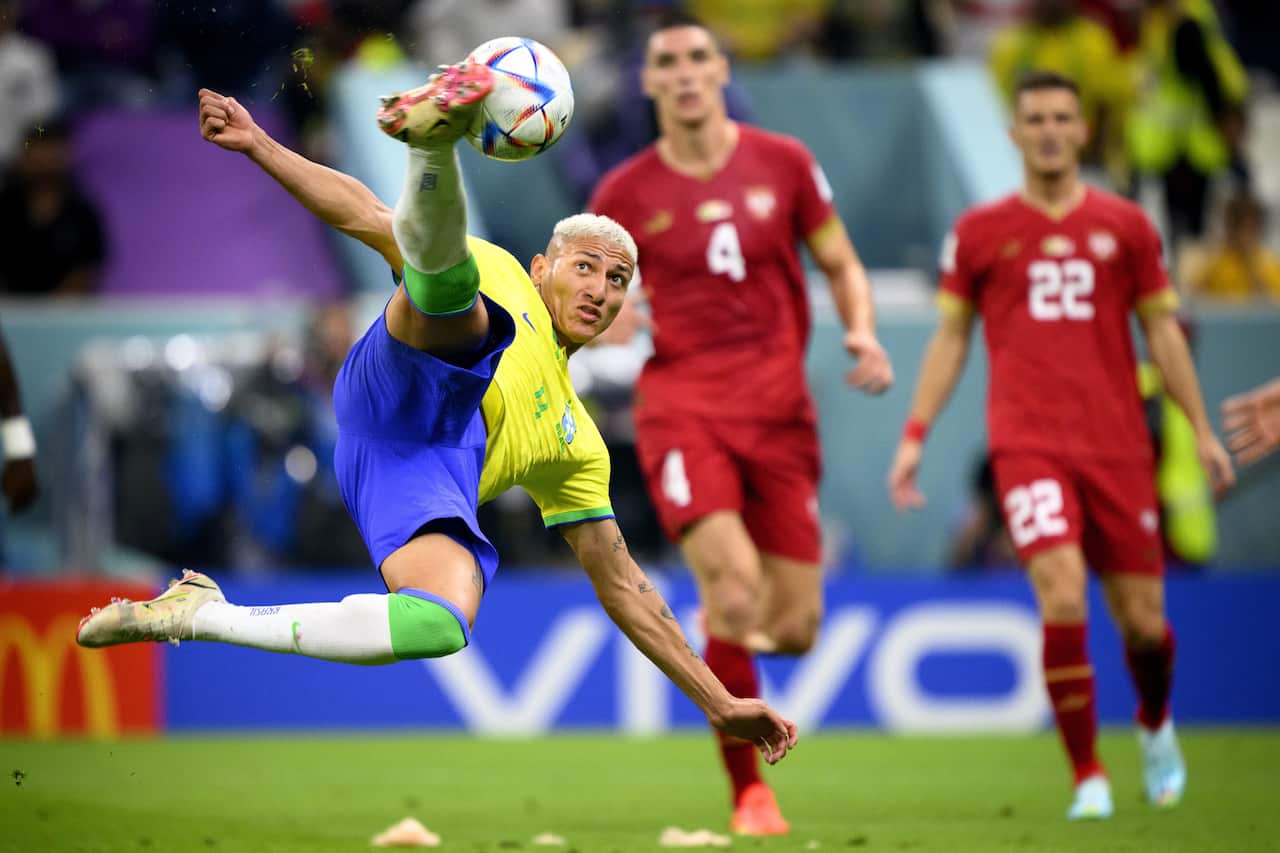 Brazil's forward Richarlison scores in front of Serbia's Nikola Milenkovic (C) and Darko Lazovic (R) during the FIFA World Cup 2022 group G match between Brazil and Serbia
