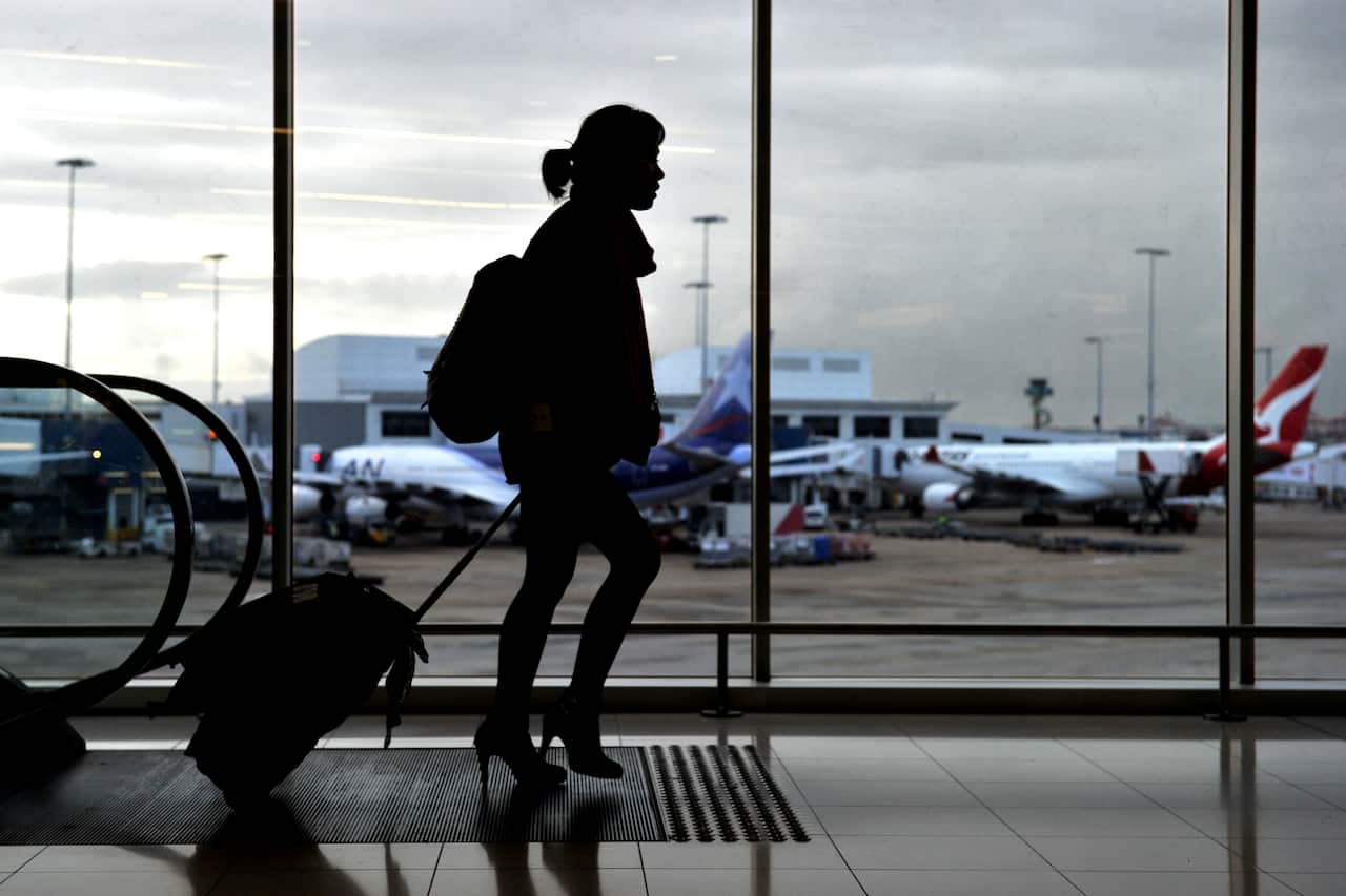 Silhouette of a woman walking through an airport.