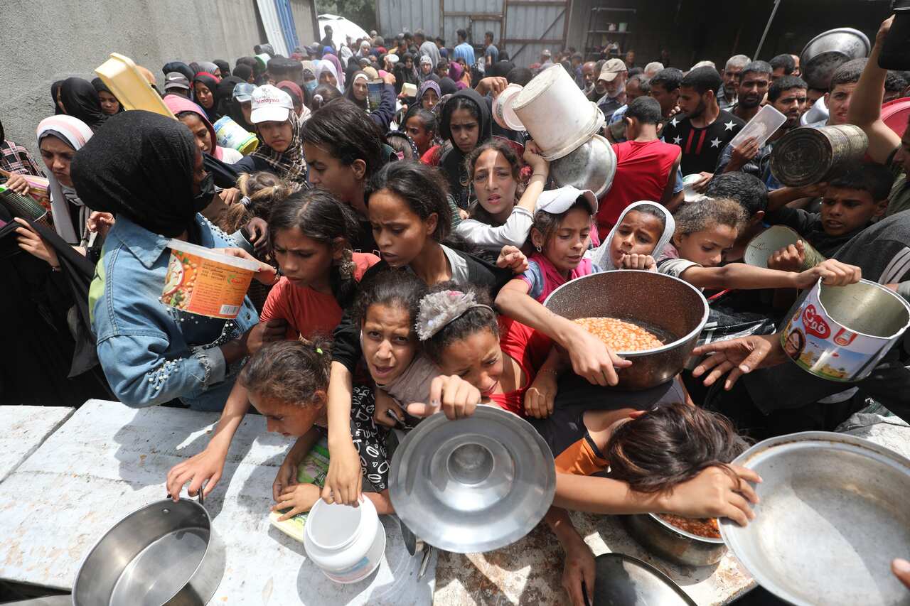 A large group of children, some holding buckets.