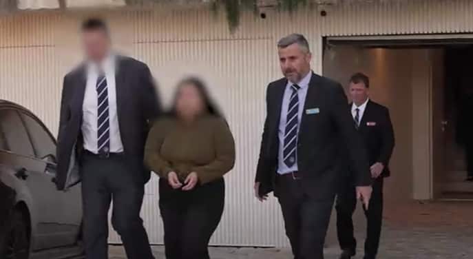 Police officers escorting a woman from a property.