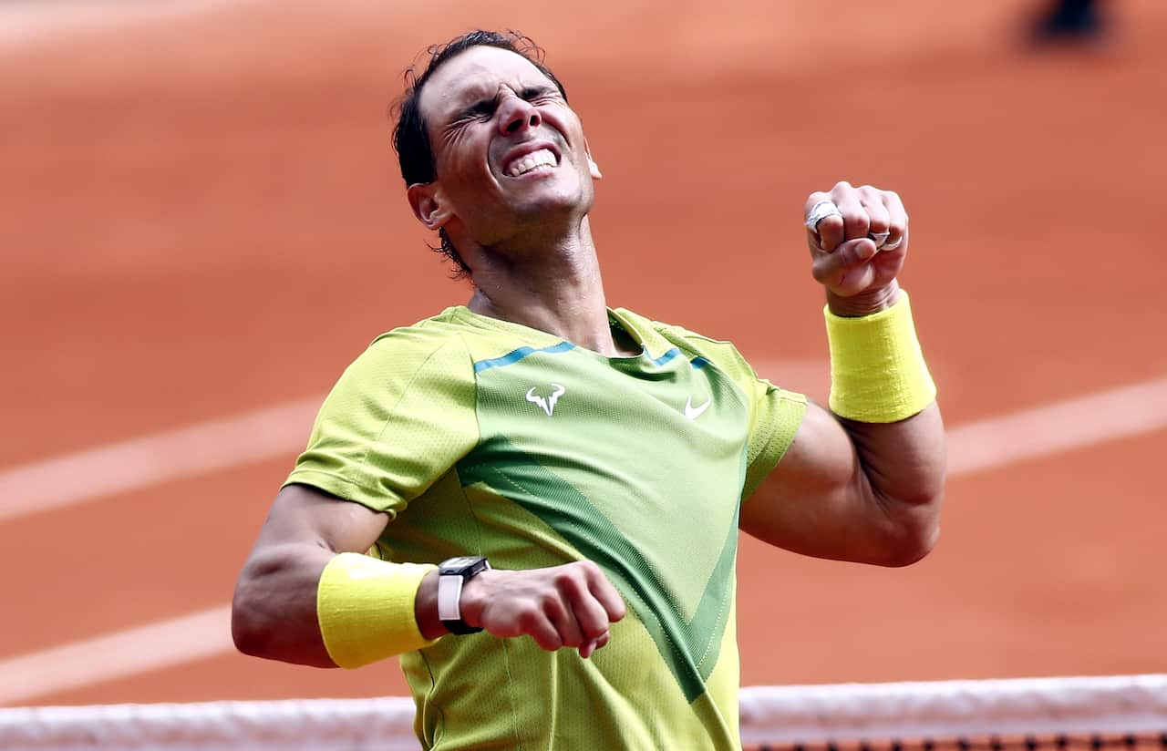 Nadal raises his fist in the air while closing his eyes, in celebration. 