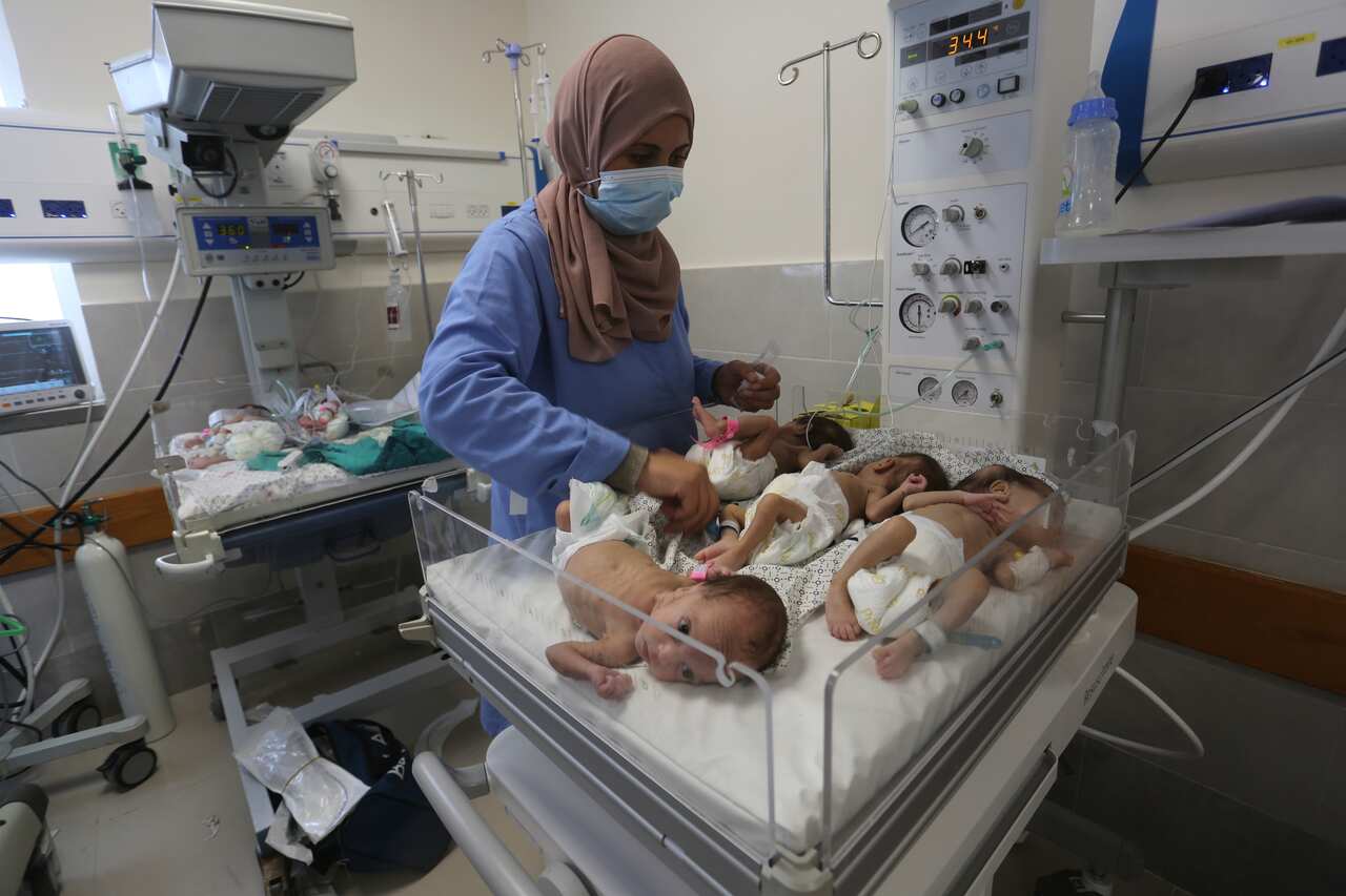 A nurse inspects babies cradled together in hospital 