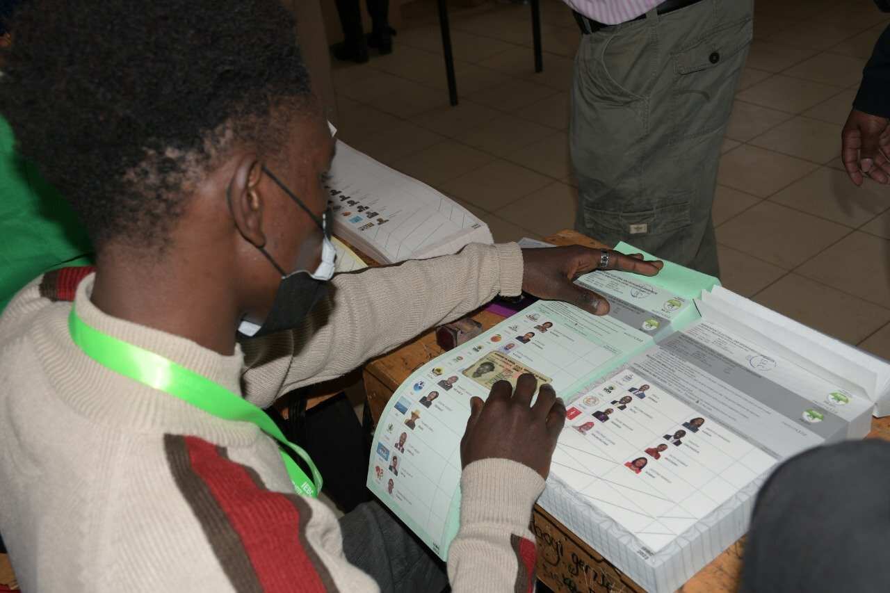 Afisa wa tume ya uchaguzi IEBC, akimhudumia mpiga kura.jpg