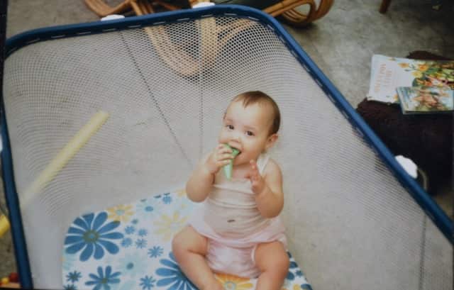 A baby plays in a playpen.