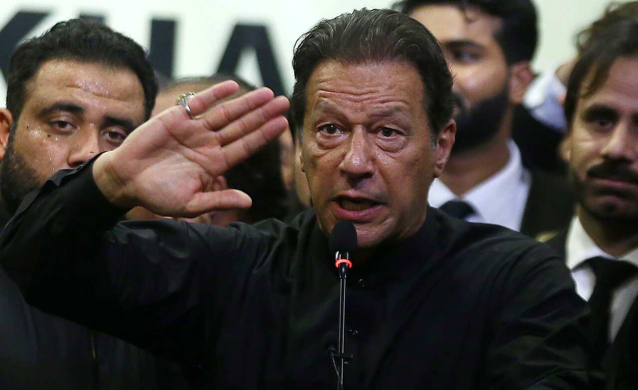 Man raises his hand, speaking on microphone. 