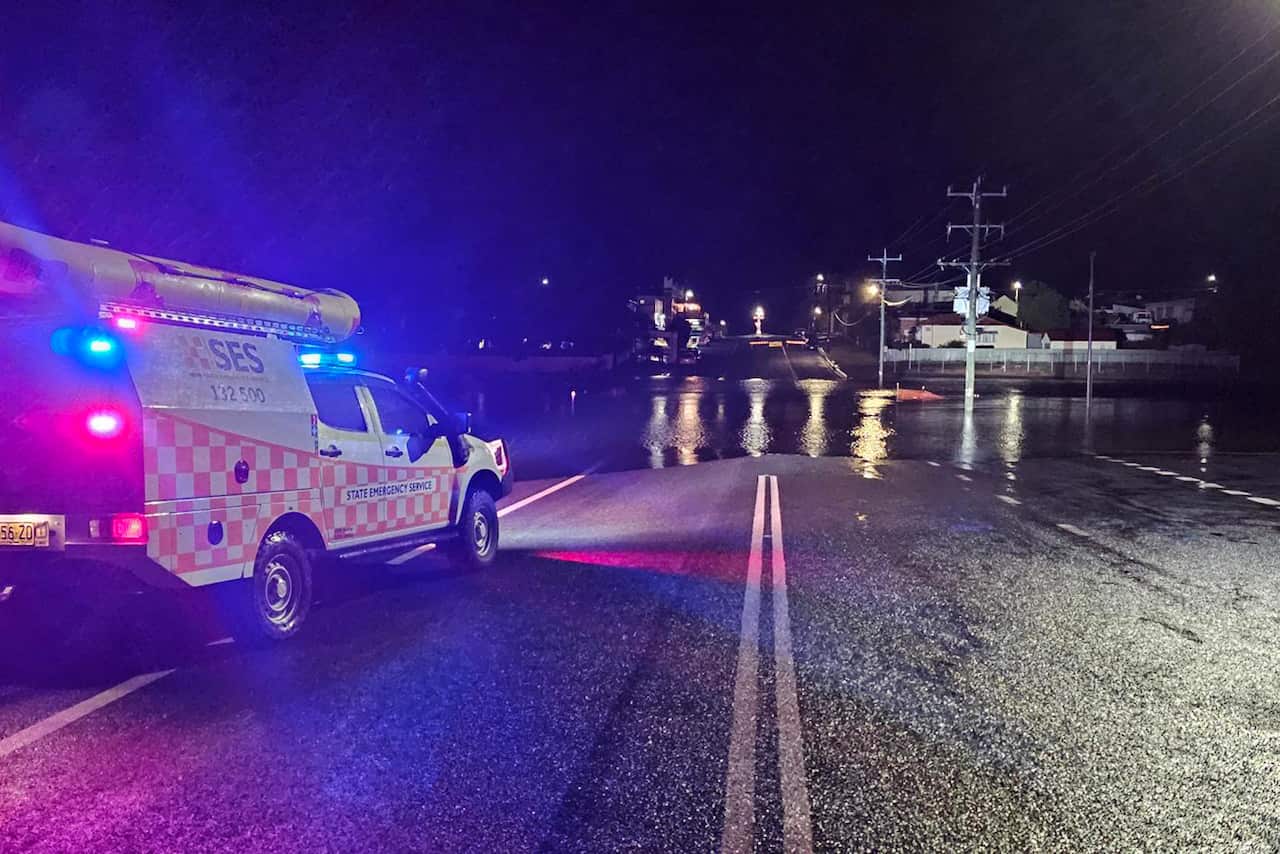 An orange and white truck parked on a road. The double lane markings are in the centre, leading into a flooded section.