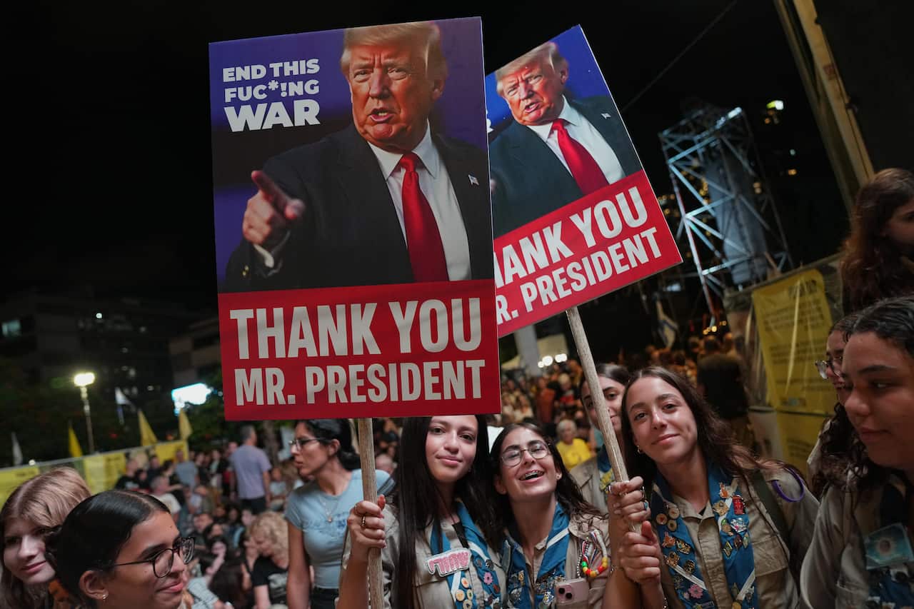 Protesters hold up signs with images depicting the US President Donald Trump at a rally.