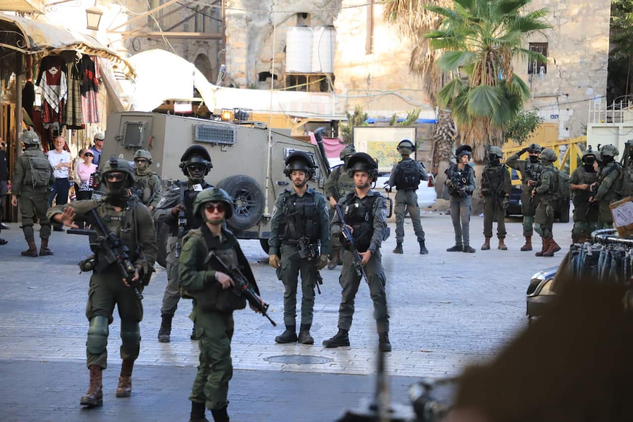 A group of soldiers in a city square, holding rifles.
