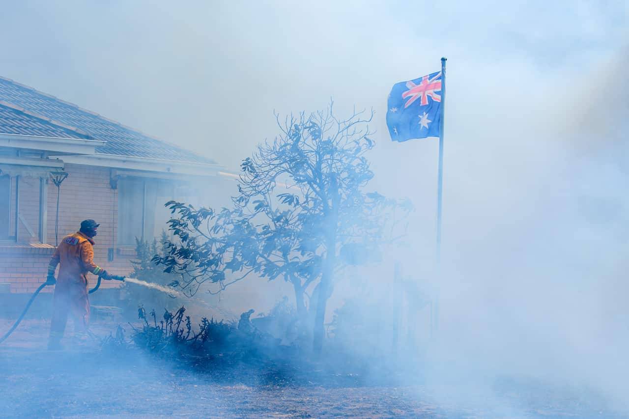 A firefighter putting out a fire in front of a house
