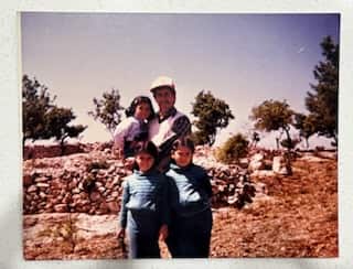 a retro film photo of a man hlding a young girl with two girls standing in front of him
