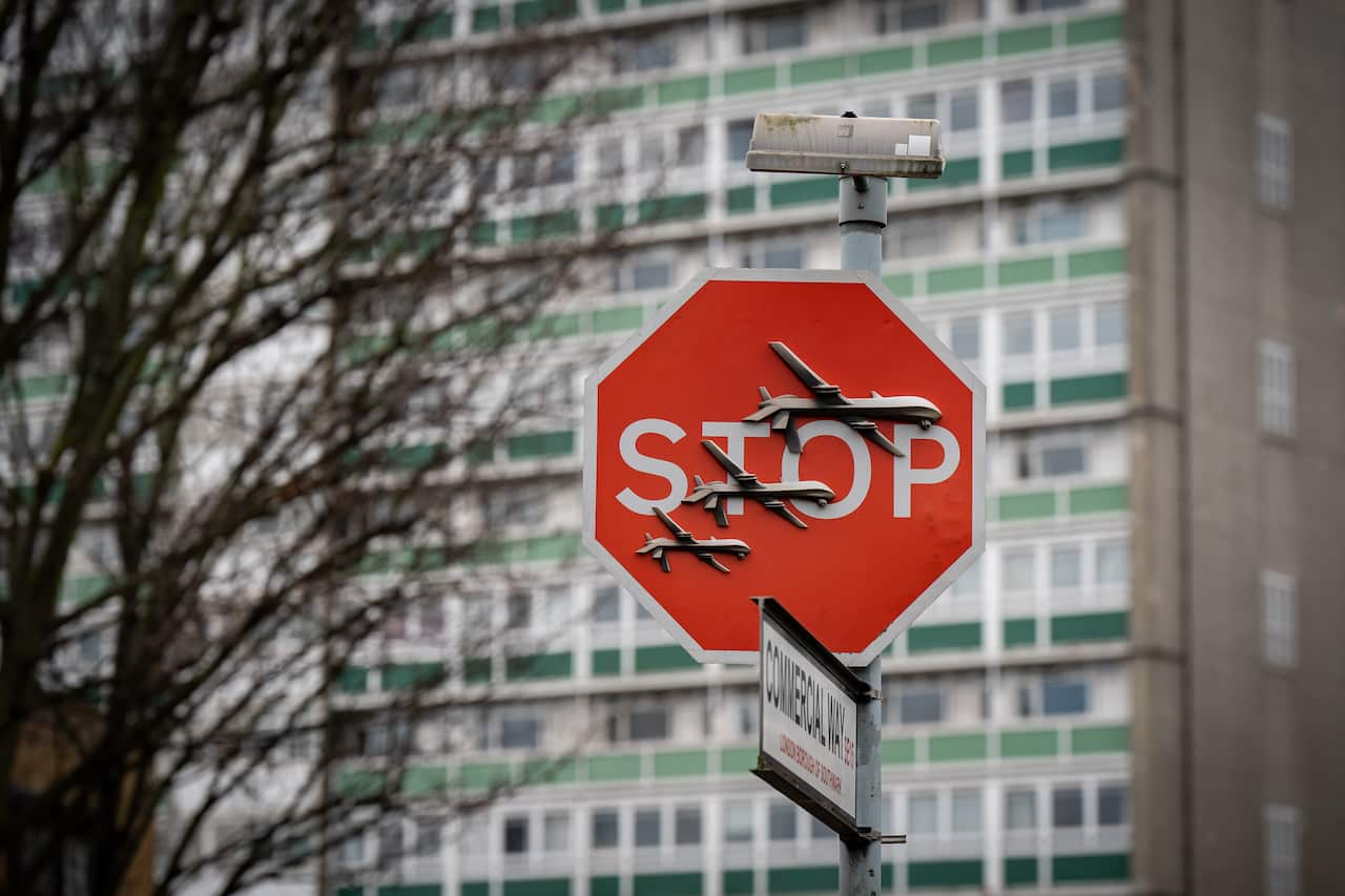 A stop sign with what appears to be three drones on it