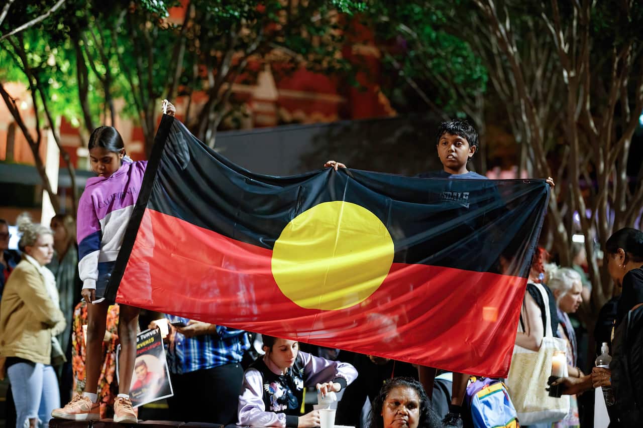 Children hold Aboriginal flag during a candlelight vigil