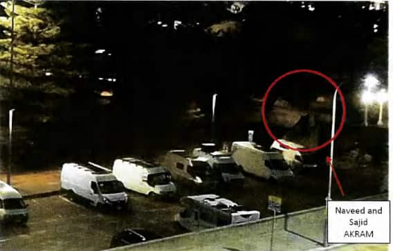 Vista aérea de un estacionamiento por la noche. Dos hombres están rodeados de rojo.