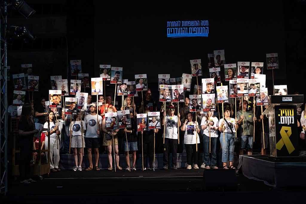 A group of demonstrators carry placards with people's faces on them.