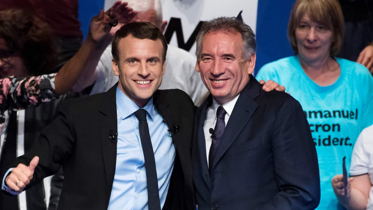 Emmanuel Macron standing next to Francois Bayrou, both smiling.