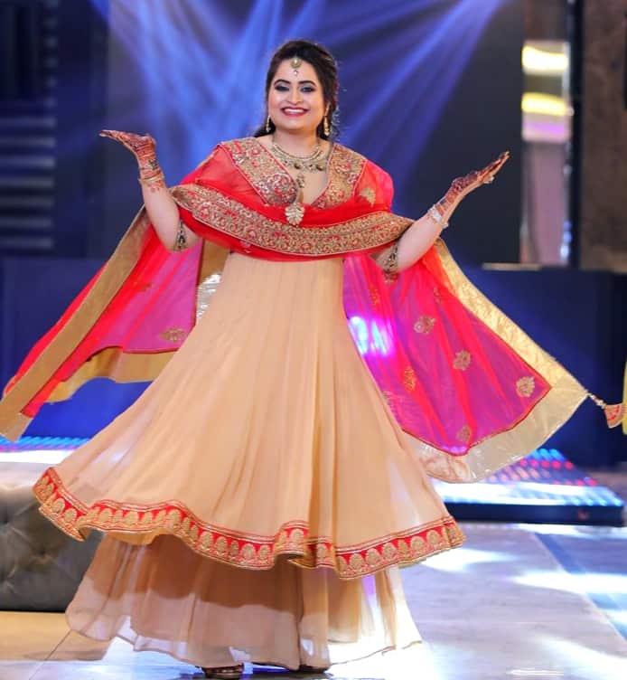 A woman in a traditional Indian suit is twirling.