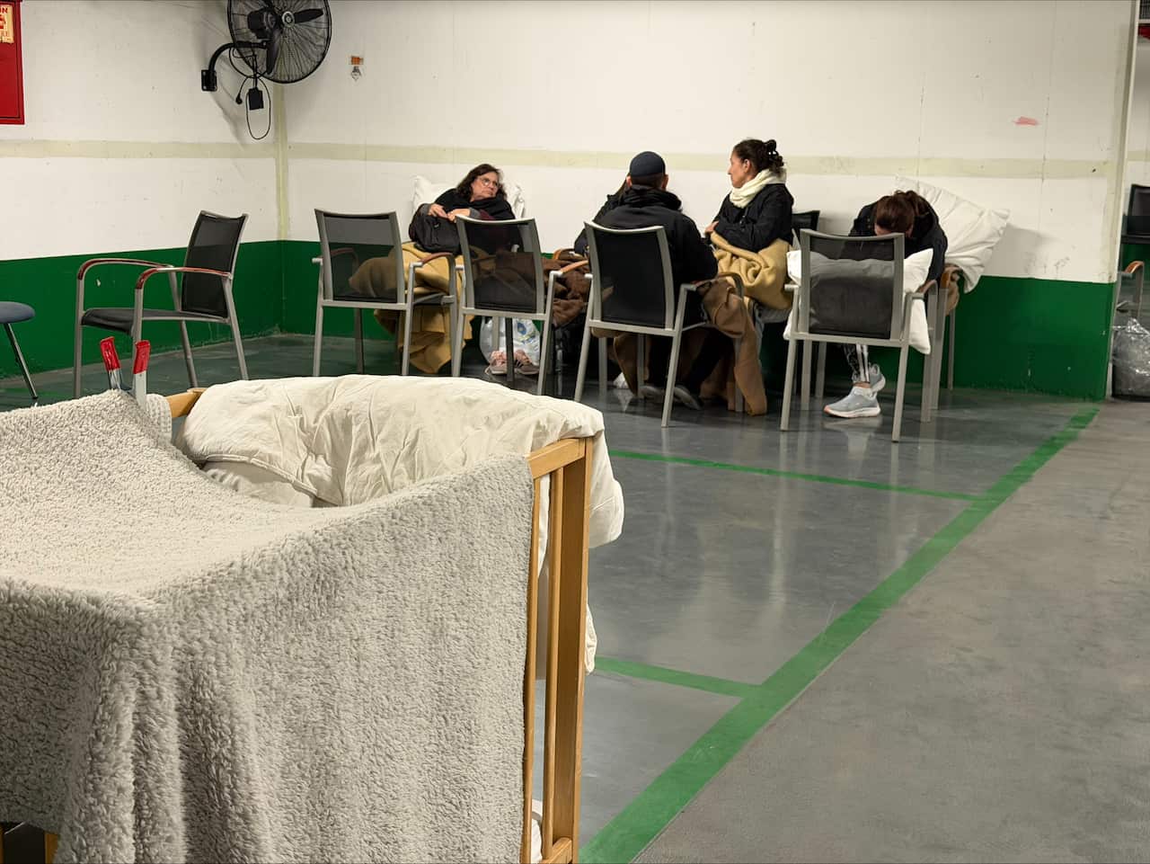 People sitting on chairs in an underground car park.