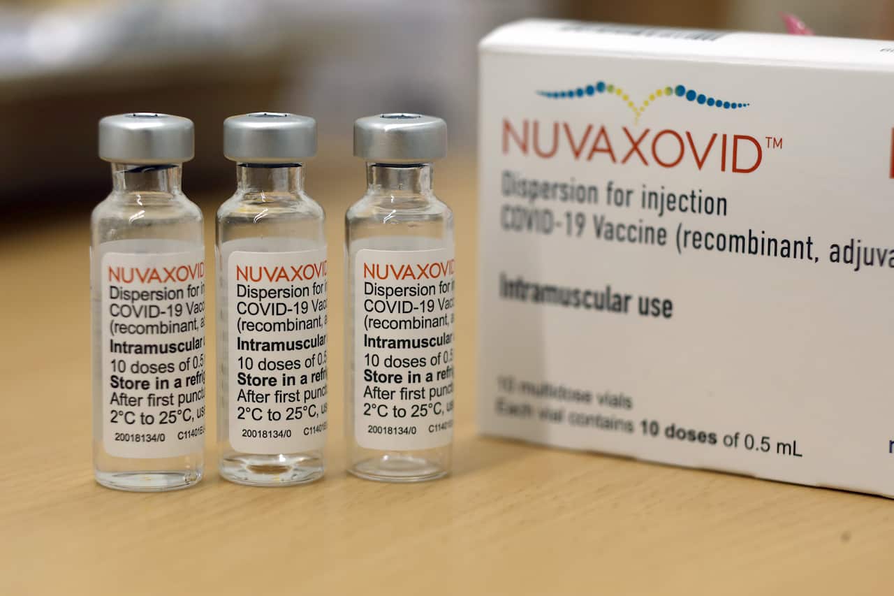 Three glass vials on a wood table, next to a cardboard packet