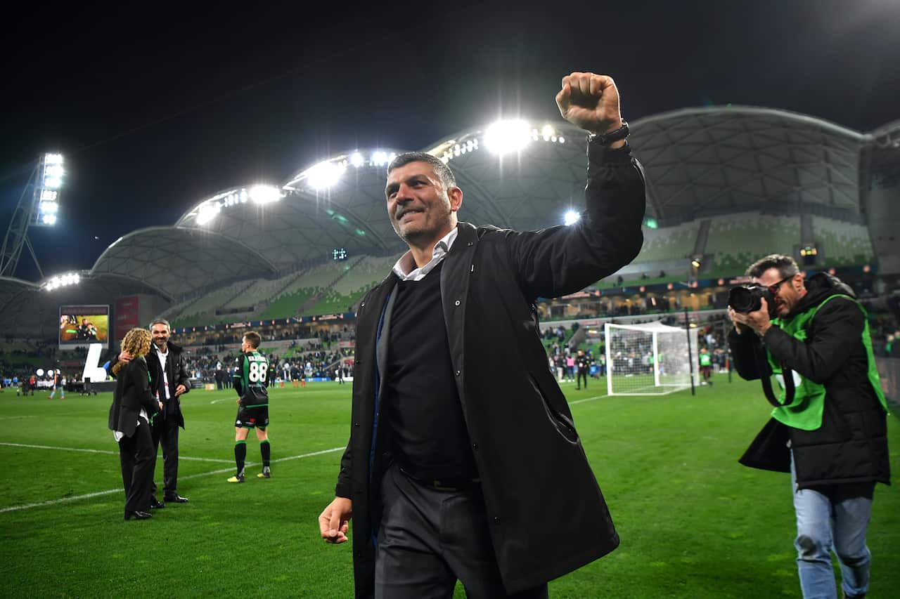 John Aloisi walking on a football field and holding up his left hand in a fist
