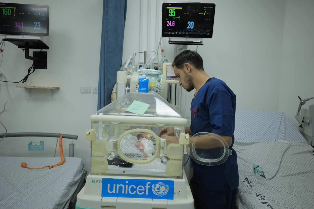 A doctor attends to a baby in a neo-natal incubator