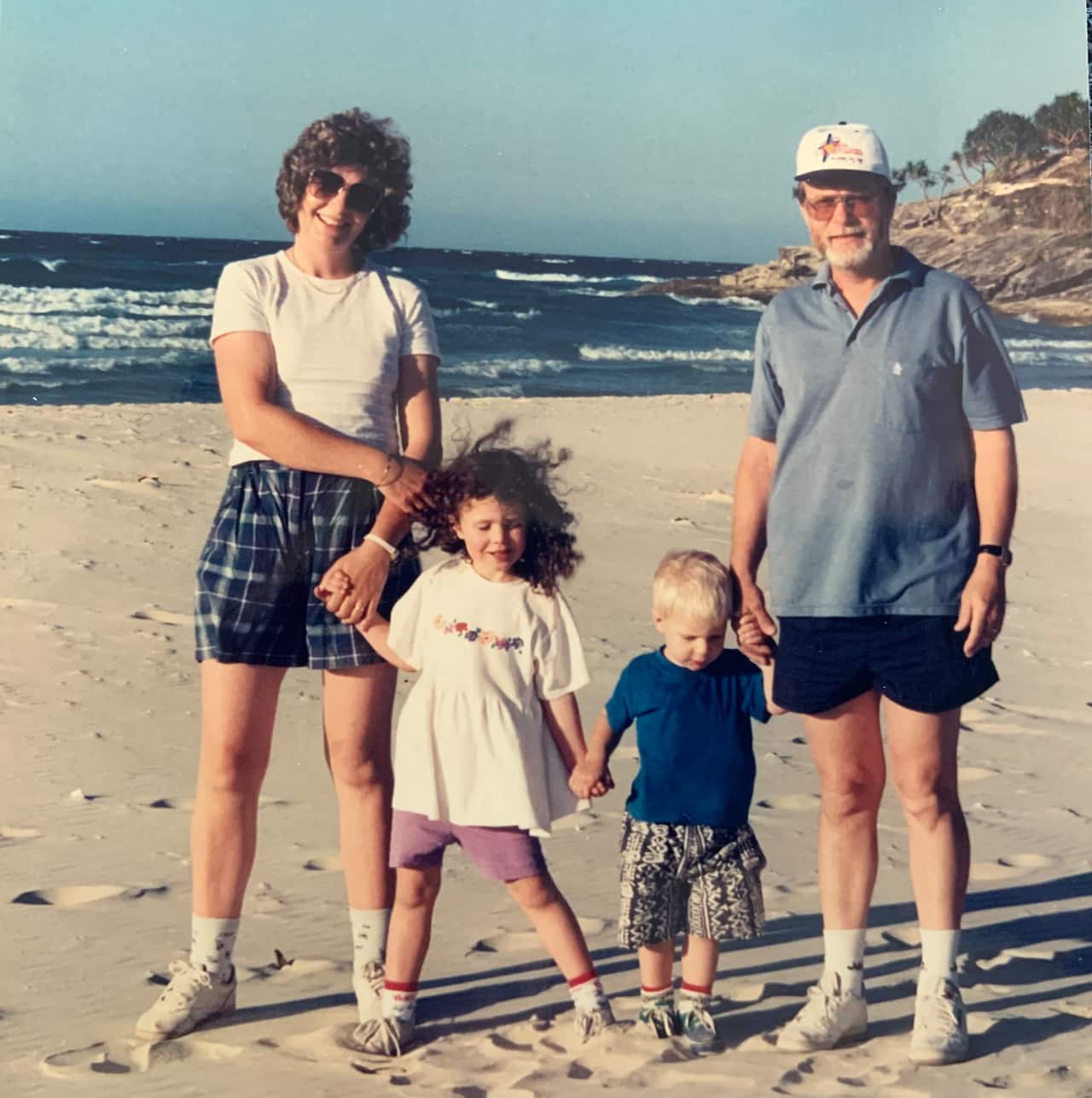 a family photo of a mum and dad and boy and girl toddlers on a beach
