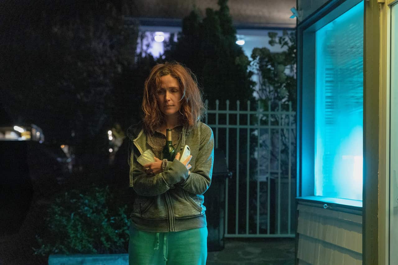 A woman at night holding a bottle of wine.