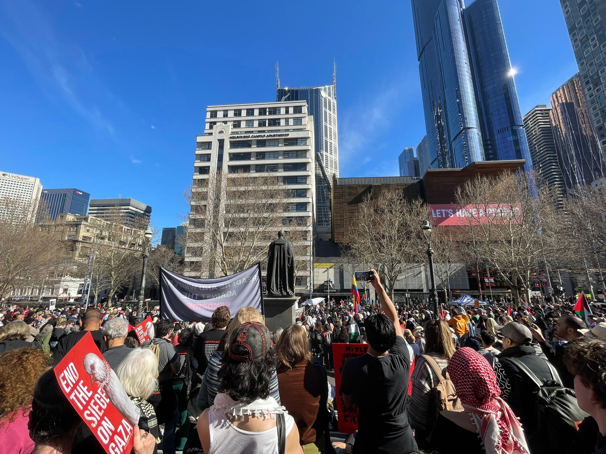 A crowd of protesters gathered in front of a statue