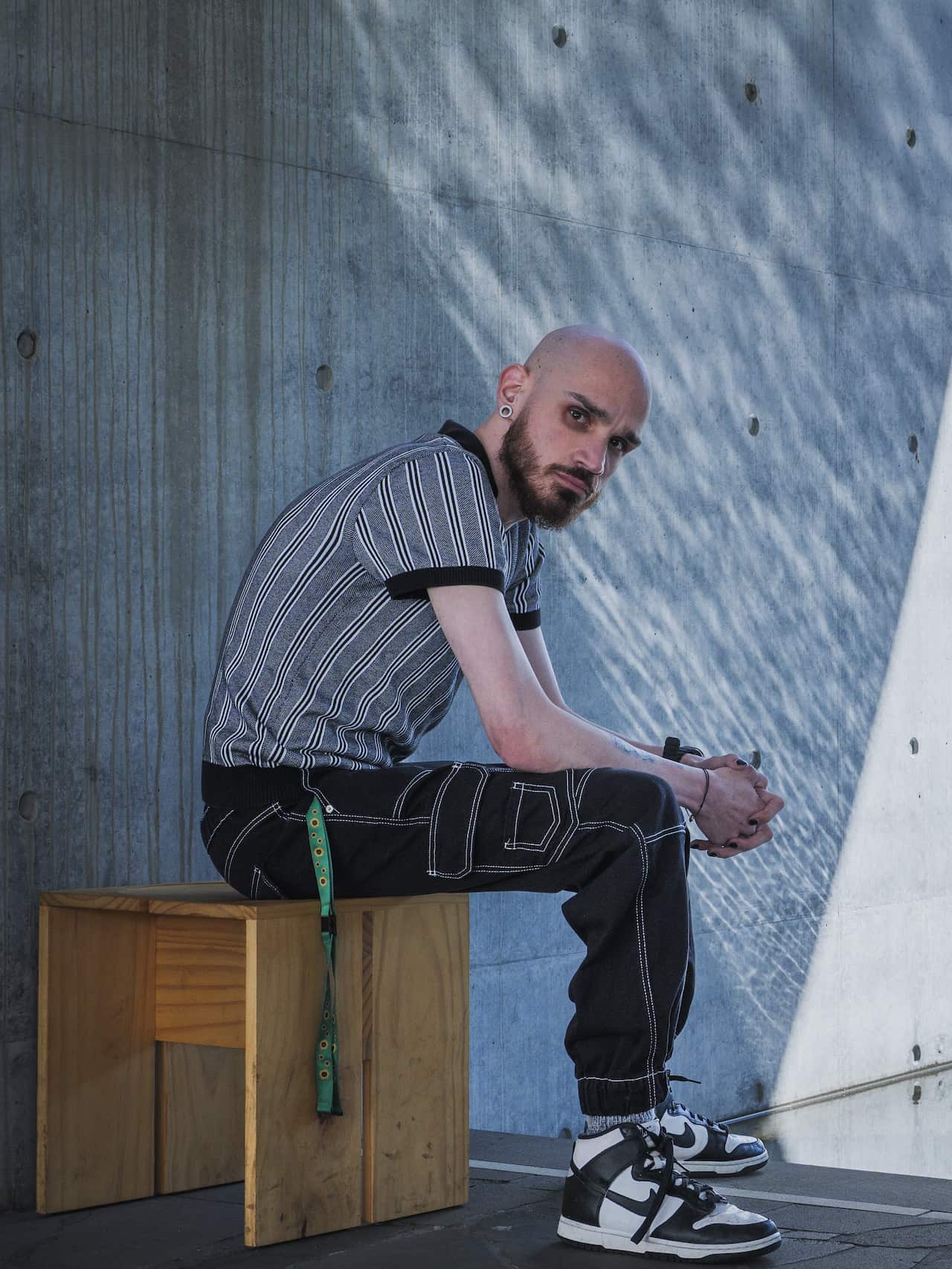 A man sits on a wooden bench outdoors.