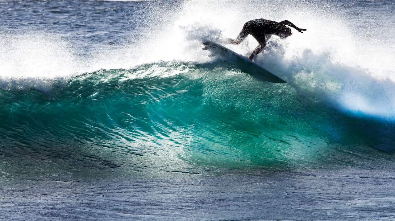 A surfer tries to stay on the surfboard while riding a wave