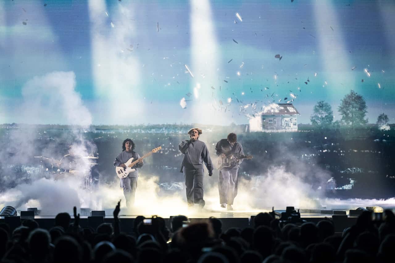 Three performers wearing grey performing on stage at Eurovision
