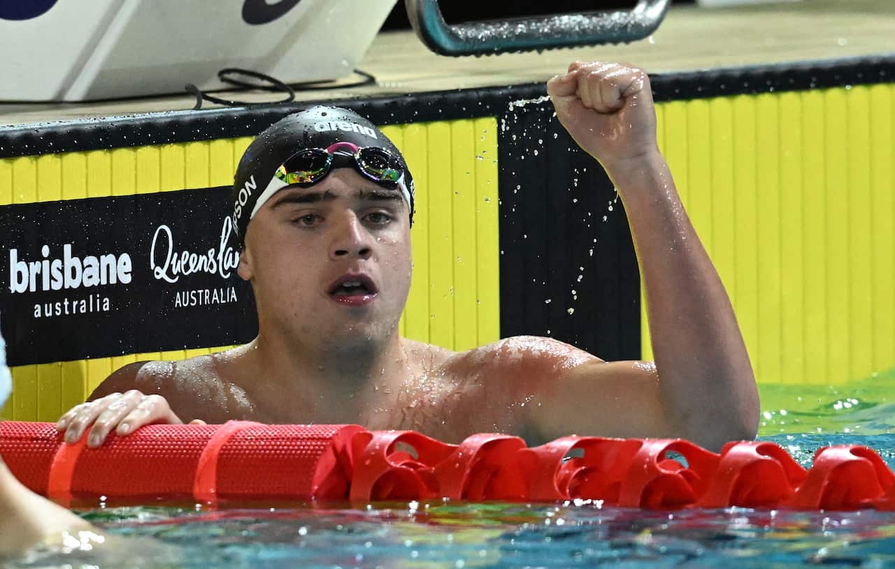 A male swimmer hold his arm up in celebration in a pool