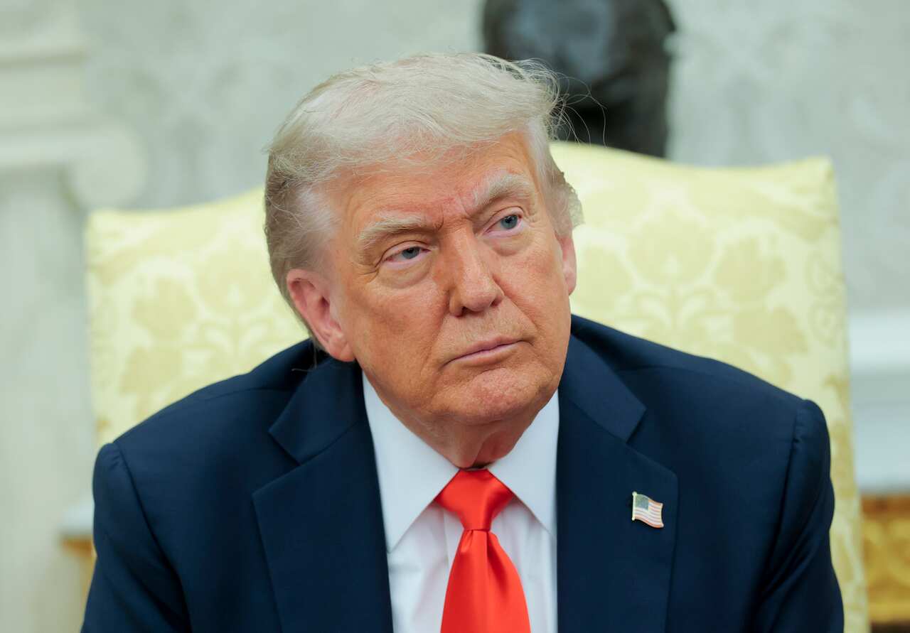 Donald Trump, wearing a blue suit and sitting in a yellow chair.