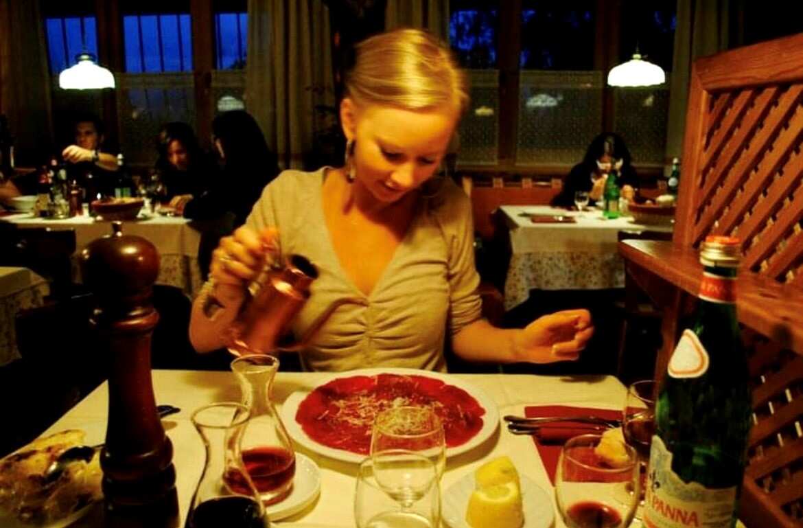 Kimberley Mitchell in a restaurant pouring oil on carpaccio.